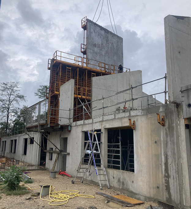 Chantier de construction avec une grue soulevant un mur en béton, des échafaudages et des échelles à Rochefort en Charente-Maritime 17