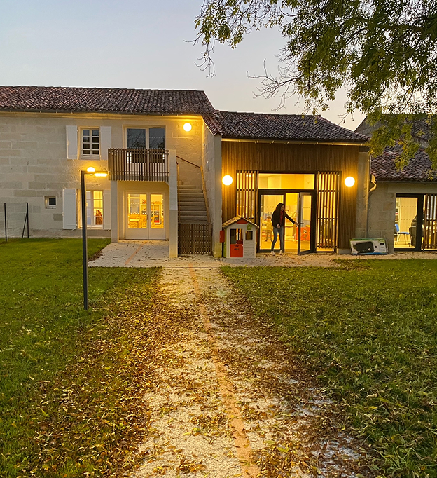 Façade d'un bâtiment en pierre avec lumières allumées et feuilles d'automne sur l'allée à Rochefort en Charente-Maritime 17