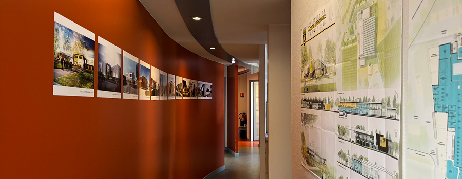 Long couloir avec des photos d'architecte incurvées sur un mur orange, plans sur le mur opposé à Rochefort en Charente-Maritime 17