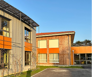 Deux bâtiments modernes avec bardage en bois et accents orange sous un ciel bleu à Rochefort en Charente-Maritime 17