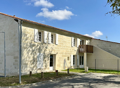 Bâtiment en pierre avec des volets blancs, un balcon en bois et un ciel bleu nuageux à Rochefort en Charente-Maritime 17